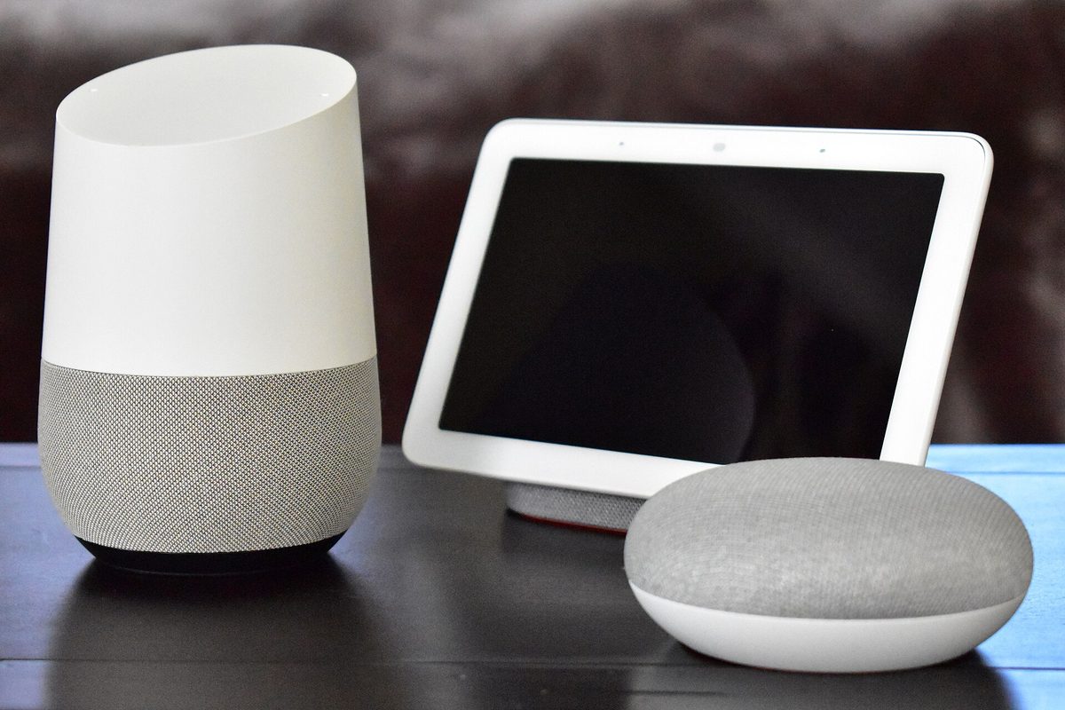 Une enceinte Google Home, un écran Google Home Hub et une Google Home Mini sur une table.