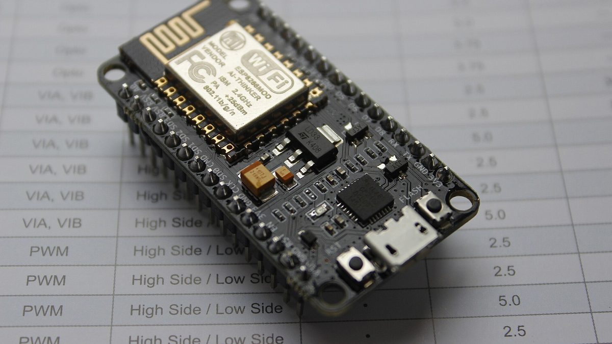 A NodeMCU development board built around an ESP8266 Wi-Fi chip, lying on a printed sheet.