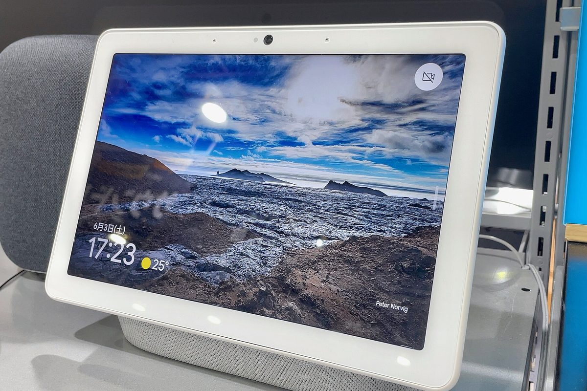 A Google Nest Hub Max smart display on a shelf showing a landscape photo and the time.
