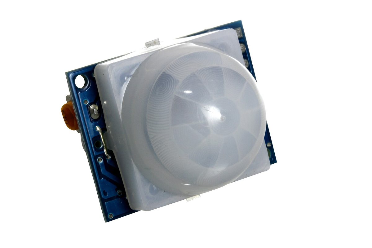 Un module détecteur de mouvement PIR avec son dôme blanc à facettes sur une carte bleue.